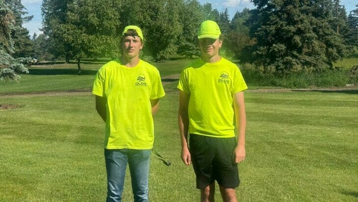 Two high school students standing on the green at the Olds golf course