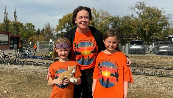 A staff member and two students wearing orange shirts with "every child matters" written on them